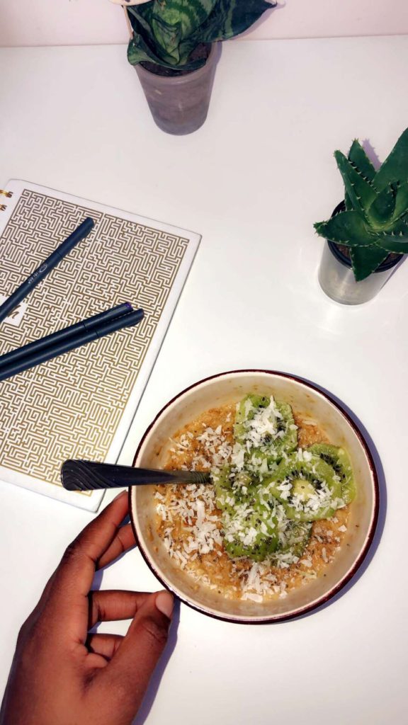 Oatmeal bowl topped with kiwi and unsweetened coconut flakes.